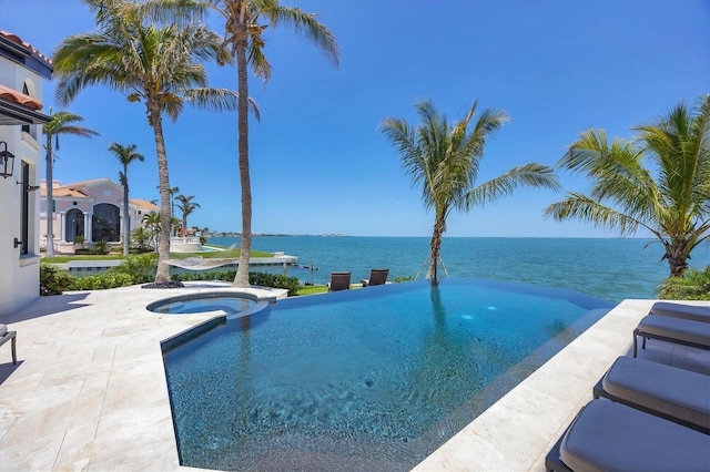 view of swimming pool with a water view, a patio area, and a pool with connected hot tub