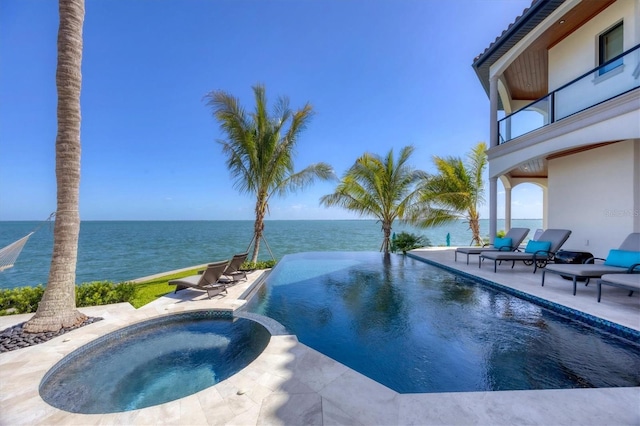 view of pool featuring a pool with connected hot tub, a patio, and a water view