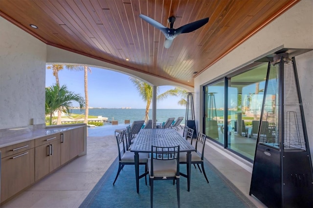 view of patio / terrace featuring a water view, outdoor dining space, and ceiling fan