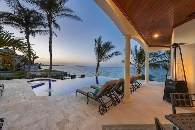 view of patio / terrace featuring a water view and an infinity pool