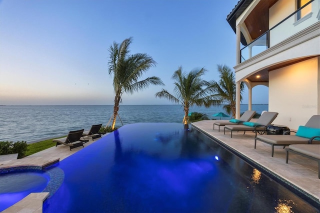 view of swimming pool with a water view, a patio, and an infinity pool