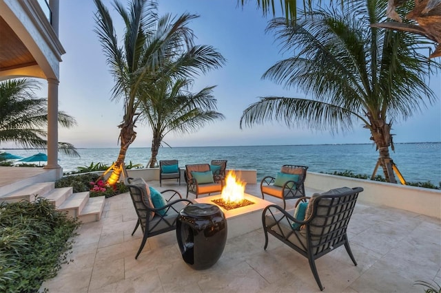 patio terrace at dusk featuring a fire pit and a water view