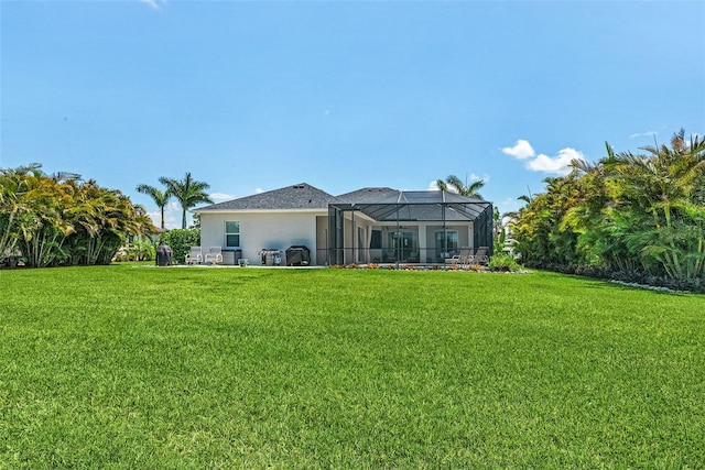 back of property with a lanai, stucco siding, and a yard