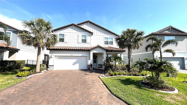 13422 Flat Woods Ter, Bradenton, FL 34211 - view of front facade featuring a garage, decorative driveway, a tiled roof, stucco siding, and board and batten siding