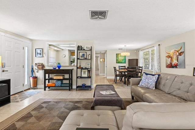 tiled living area featuring baseboards and visible vents