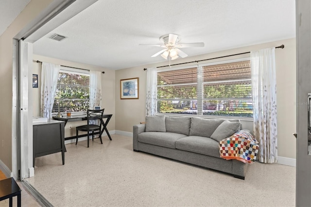 living room with baseboards, ceiling fan, speckled floor, and visible vents