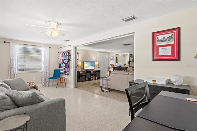living room with light speckled floor, baseboards, a ceiling fan, and visible vents