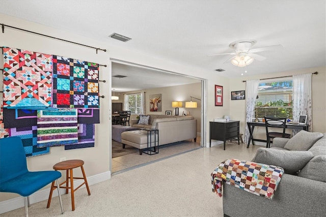 living area featuring baseboards, a ceiling fan, speckled floor, and visible vents