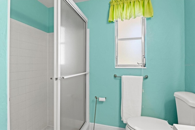 full bathroom featuring toilet, baseboards, and a stall shower