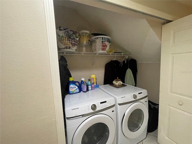 clothes washing area featuring laundry area, washer and clothes dryer, a textured wall, and tile patterned flooring