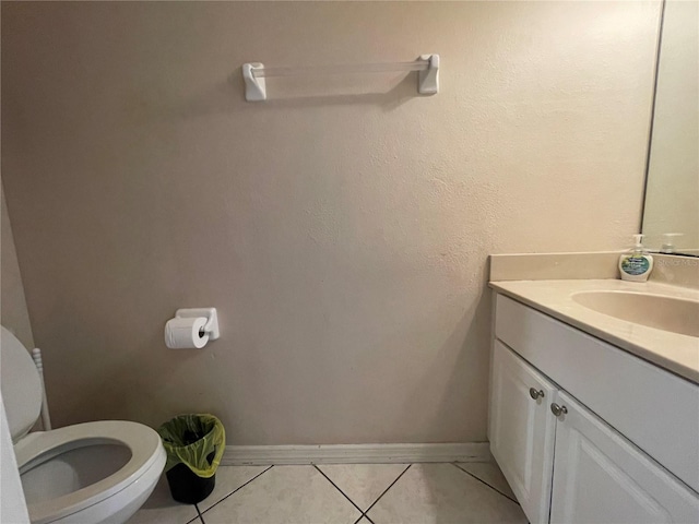 half bathroom with vanity, tile patterned flooring, baseboards, and toilet