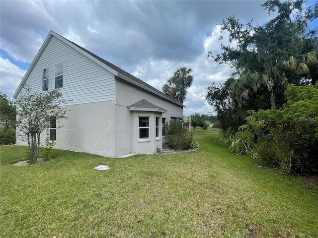 view of side of home featuring stucco siding and a yard