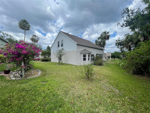 view of side of home featuring stucco siding and a yard