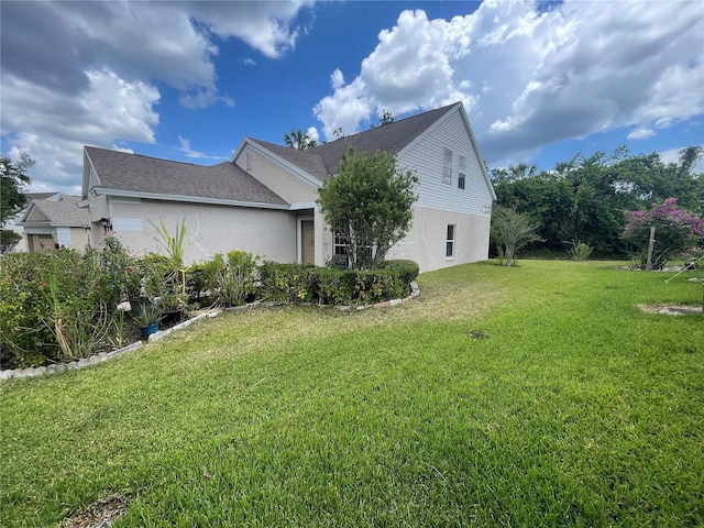 view of side of property featuring stucco siding and a yard