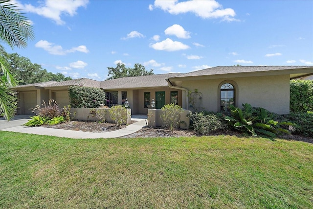 single story home with stucco siding, an attached garage, a front yard, and driveway