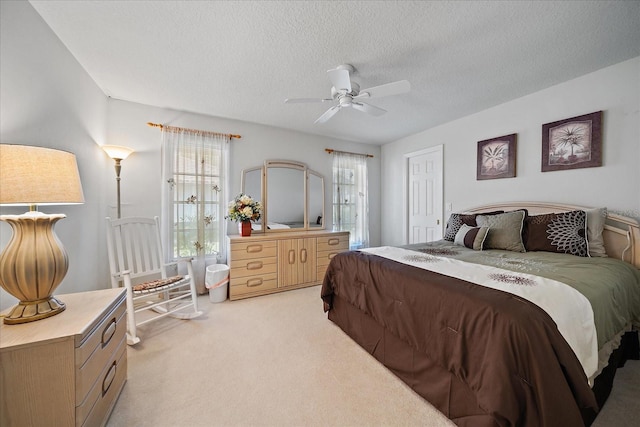 bedroom featuring light colored carpet, a textured ceiling, and a ceiling fan