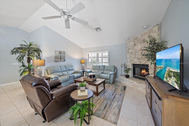 living area featuring vaulted ceiling, a stone fireplace, light tile patterned floors, ceiling fan, and a textured ceiling