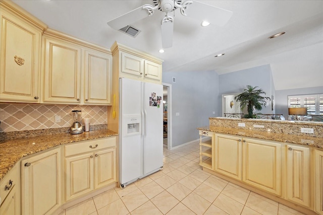 kitchen with white refrigerator with ice dispenser, cream cabinets, light tile patterned floors, a ceiling fan, and decorative backsplash