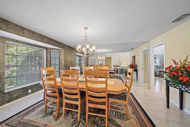 dining space with light tile patterned floors, a chandelier, a textured ceiling, and baseboards