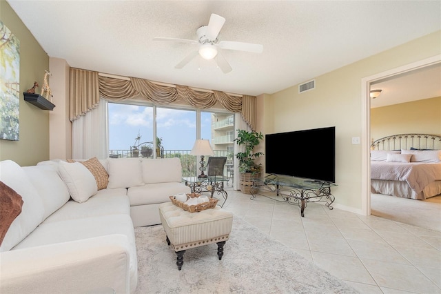tiled living area featuring a ceiling fan, baseboards, and a textured ceiling