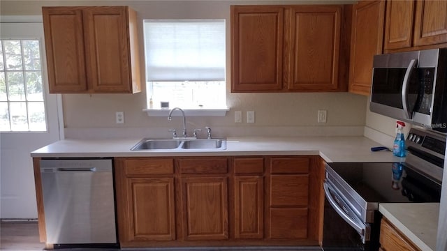kitchen with a sink, brown cabinetry, light countertops, and appliances with stainless steel finishes