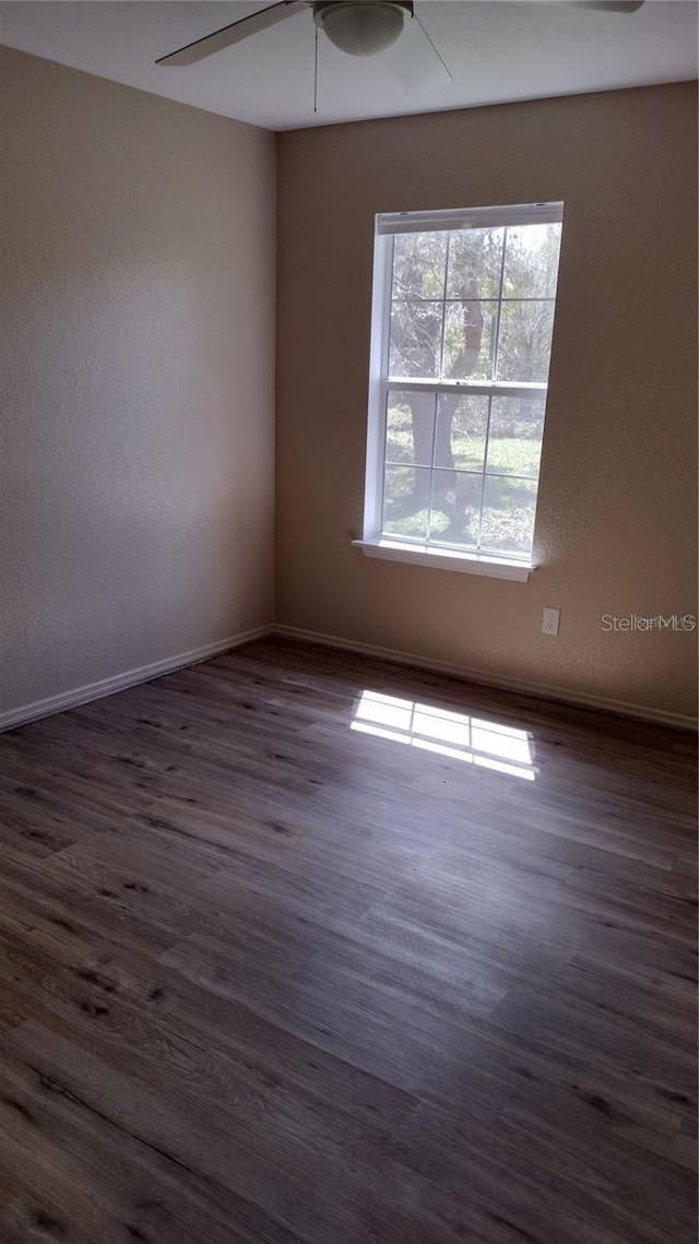 unfurnished room with baseboards, a ceiling fan, and dark wood-style floors