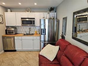 kitchen with recessed lighting, a sink, white cabinets, tasteful backsplash, and appliances with stainless steel finishes