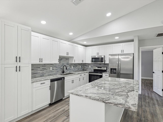 8304 Fishhawk Ave, New Port Richey, FL 34653 - kitchen with appliances with stainless steel finishes, a sink, wood finished floors, lofted ceiling, and tasteful backsplash