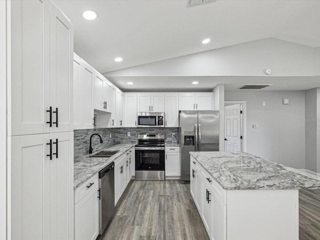 8304 Fishhawk Ave, New Port Richey, FL 34653 - kitchen with appliances with stainless steel finishes, a center island, vaulted ceiling, wood finished floors, and a sink