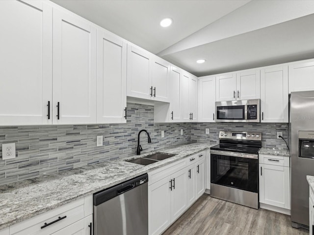 8304 Fishhawk Ave, New Port Richey, FL 34653 - kitchen with a sink, white cabinetry, appliances with stainless steel finishes, and lofted ceiling