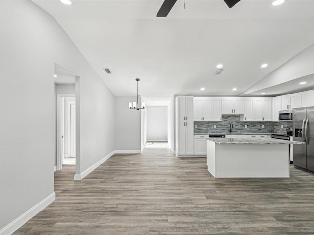 8304 Fishhawk Ave, New Port Richey, FL 34653 - kitchen featuring appliances with stainless steel finishes, a sink, ceiling fan with notable chandelier, a kitchen island, and vaulted ceiling