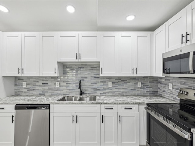 8304 Fishhawk Ave, New Port Richey, FL 34653 - kitchen featuring light stone countertops, white cabinets, tasteful backsplash, a sink, and stainless steel appliances