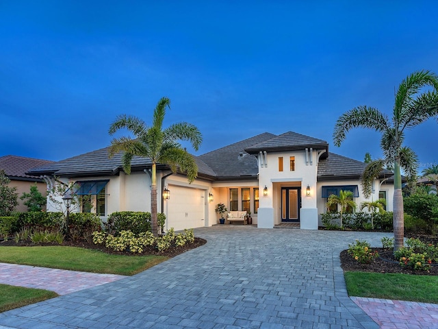view of front of home featuring decorative driveway, stucco siding, and an attached garage