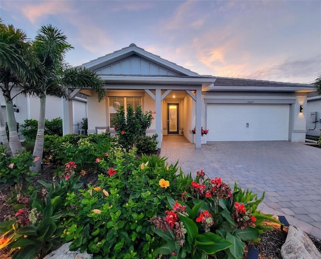 26017 Seastone Dr, Englewood, FL 34223 - view of front of home featuring an attached garage, decorative driveway, stucco siding, and board and batten siding