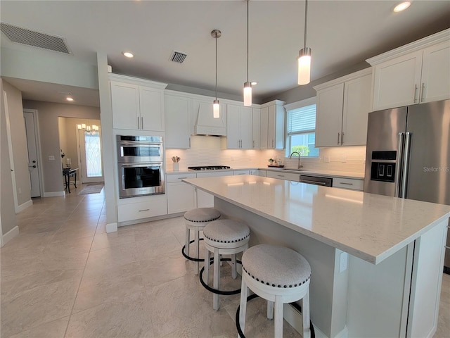 26017 Seastone Dr, Englewood, FL 34223 - kitchen with stainless steel appliances, decorative backsplash, a center island, white cabinets, and recessed lighting