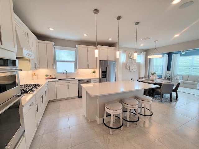 26017 Seastone Dr, Englewood, FL 34223 - kitchen featuring stainless steel appliances, a sink, a breakfast bar area, backsplash, and a center island