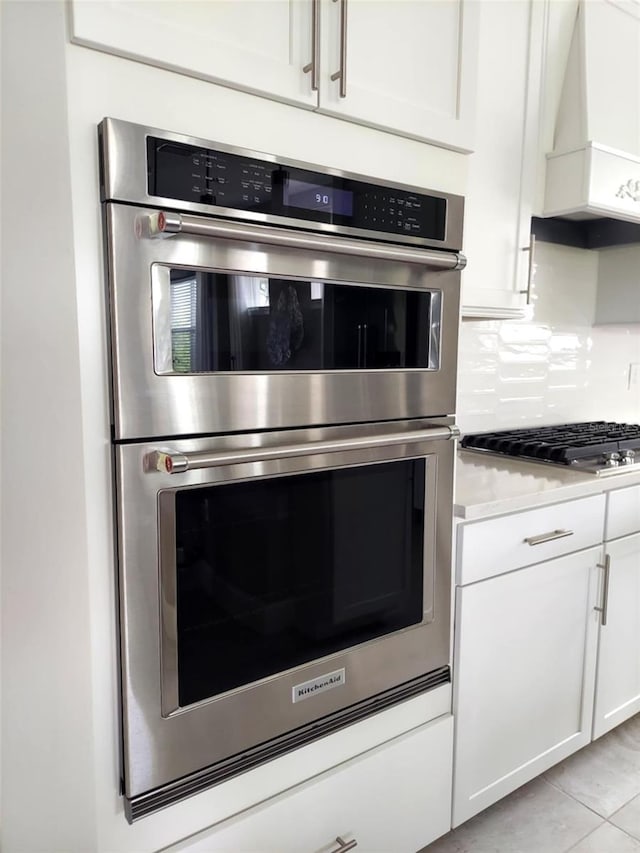 26017 Seastone Dr, Englewood, FL 34223 - kitchen featuring appliances with stainless steel finishes, premium range hood, white cabinets, light countertops, and tasteful backsplash