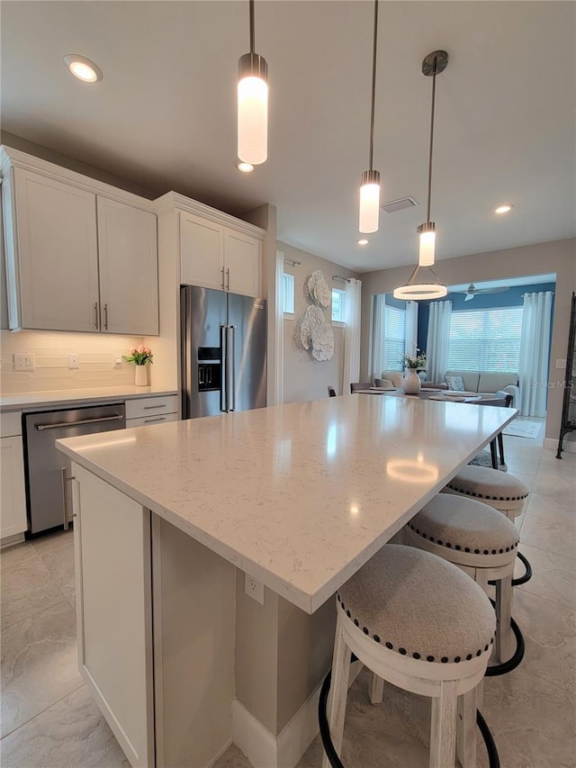 26017 Seastone Dr, Englewood, FL 34223 - kitchen with stainless steel appliances, a kitchen island, healthy amount of natural light, light stone counters, and recessed lighting