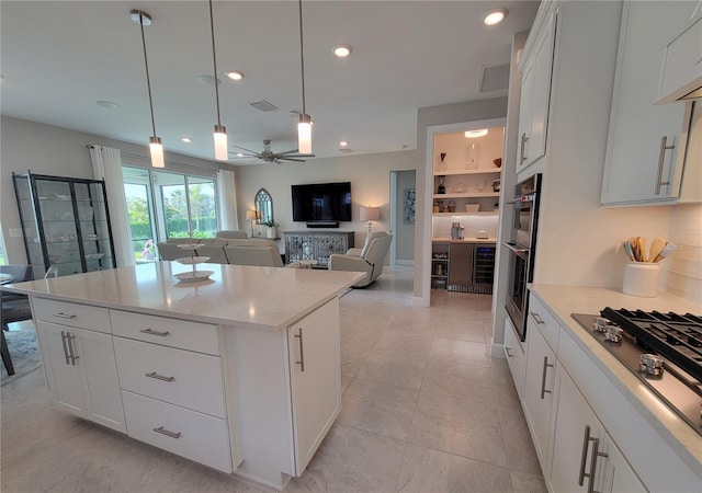 26017 Seastone Dr, Englewood, FL 34223 - kitchen featuring stainless steel gas cooktop, ceiling fan, a center island, pendant lighting, and white cabinets