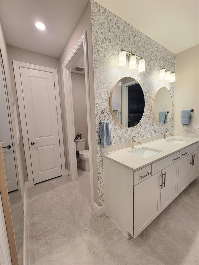 26017 Seastone Dr, Englewood, FL 34223 - full bath with double vanity, toilet, wallpapered walls, and baseboards