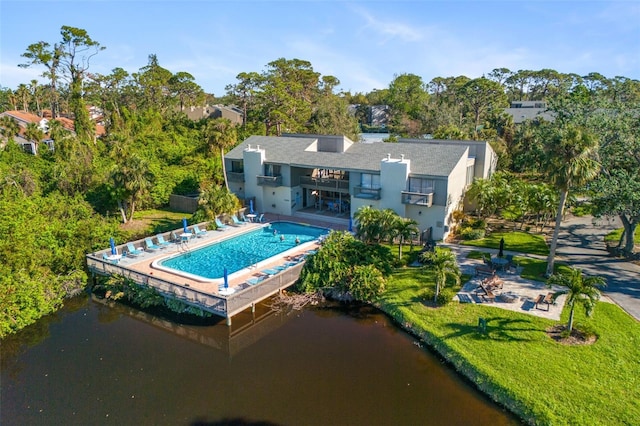 rear view of property featuring a patio, an outdoor pool, a lawn, and a balcony