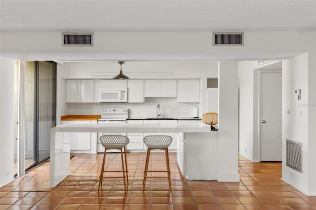 kitchen featuring visible vents, a sink, light tile patterned floors, and white appliances