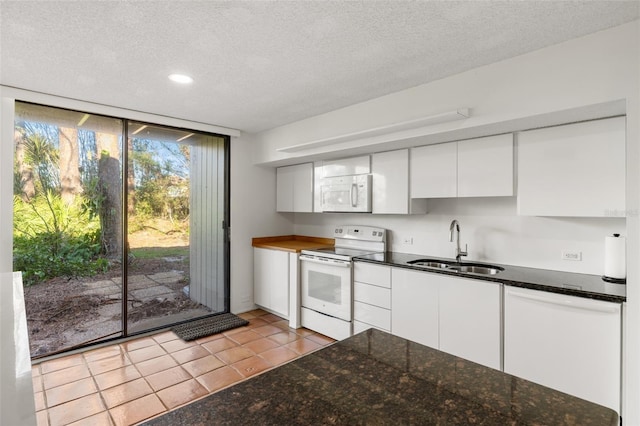kitchen featuring white cabinets, a sink, white appliances, a textured ceiling, and light tile patterned floors