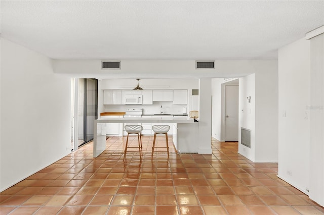 kitchen with white appliances, white cabinetry, and visible vents