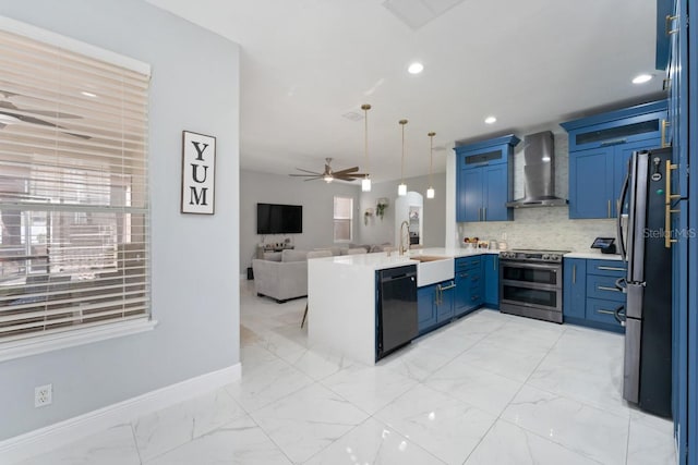 kitchen with ceiling fan, a sink, wall chimney exhaust hood, stainless steel appliances, and open floor plan