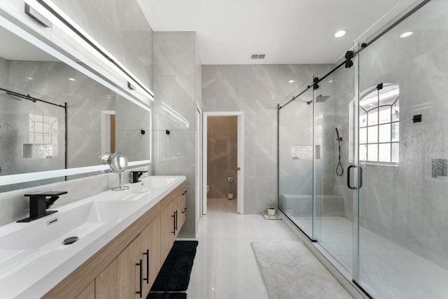 bathroom with a sink, a shower stall, double vanity, and visible vents