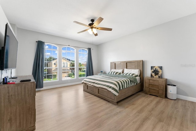 bedroom with light wood-type flooring, baseboards, and ceiling fan