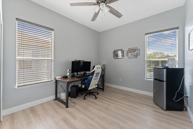 office space featuring baseboards, ceiling fan, and light wood-style flooring