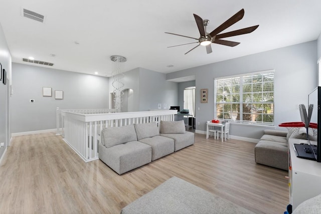 living room featuring baseboards, ceiling fan, light wood-style flooring, and visible vents