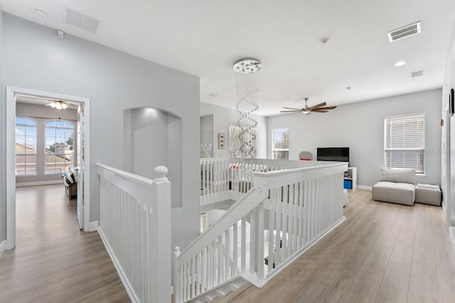 hallway featuring an upstairs landing, plenty of natural light, wood finished floors, and visible vents